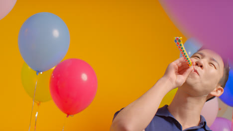 Studioporträt-Eines-Mannes-Mit-Partyhut,-Der-Geburtstag-Mit-Luftballons-Und-Partygebläse-Feiert-3